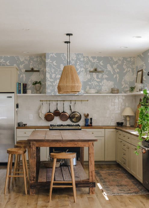 Kitchen with wooden island, stools, and floral wallpaper