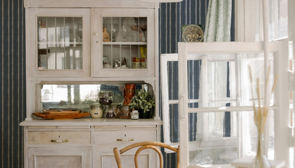 Dining room with a hutch, chairs, and a window with curtains.