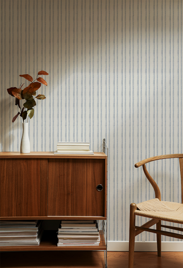 Wooden sideboard with a vase and books against a striped wall.