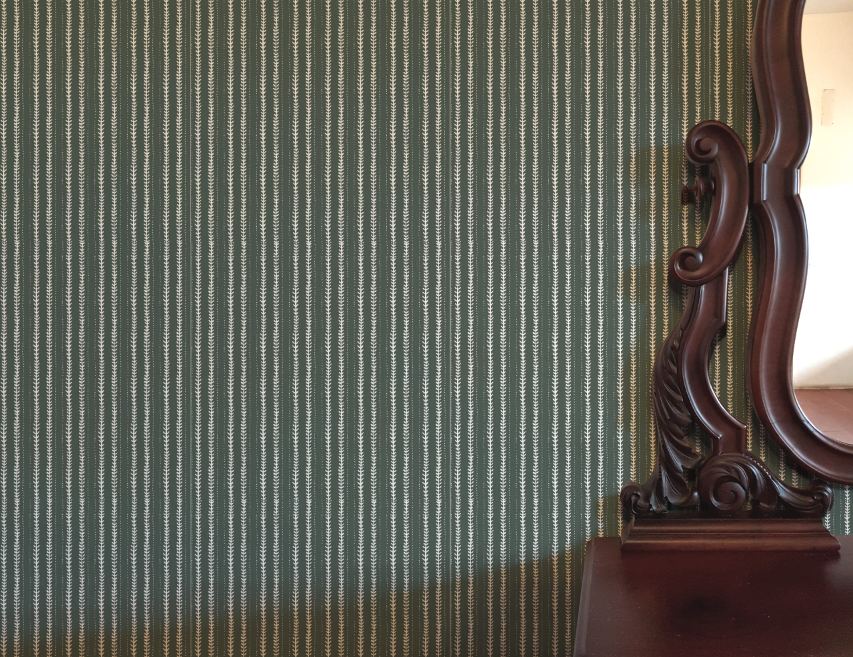 Wooden dresser with decorative mirror against a striped green wall