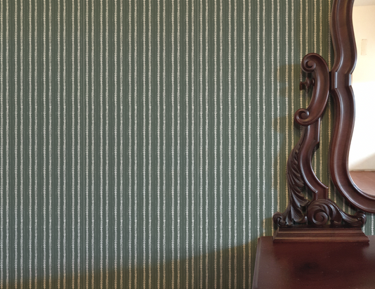 Wooden dresser with decorative mirror against a striped green wall