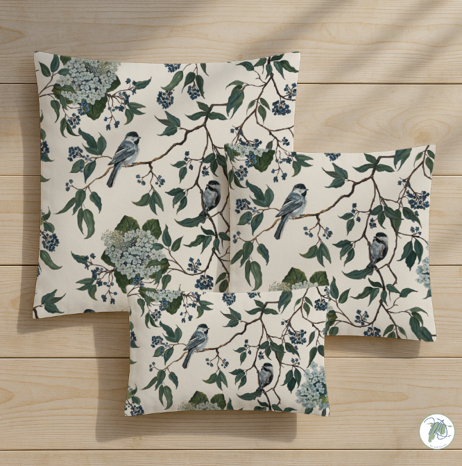 Set of three pillows with floral and bird pattern on a wooden surface