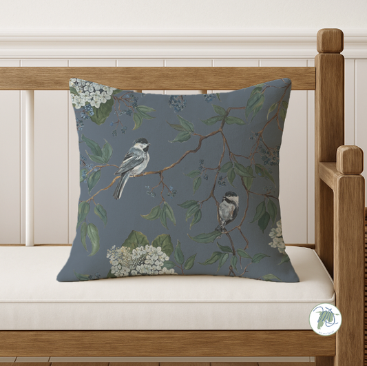 Decorative pillow with bird and floral pattern on a wooden bench.