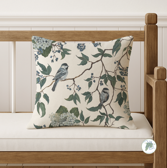Decorative pillow with bird and leaf pattern on a wooden bench