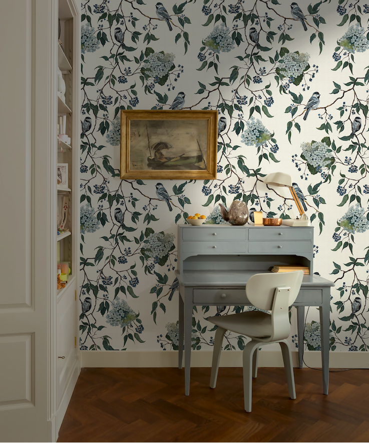 Room with floral wallpaper, desk, and chair.