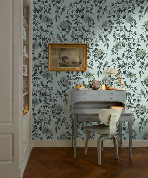 Room interior with floral wallpaper, desk, and chair.