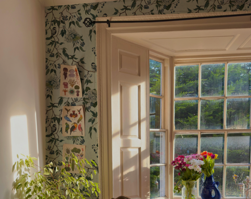 Room with floral wallpaper, a window, and decorative vases.
