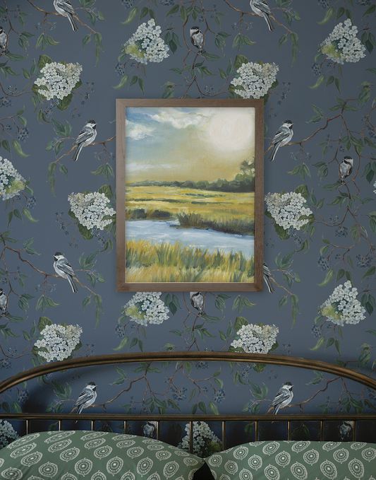 Framed landscape painting on a wall with floral and bird pattern