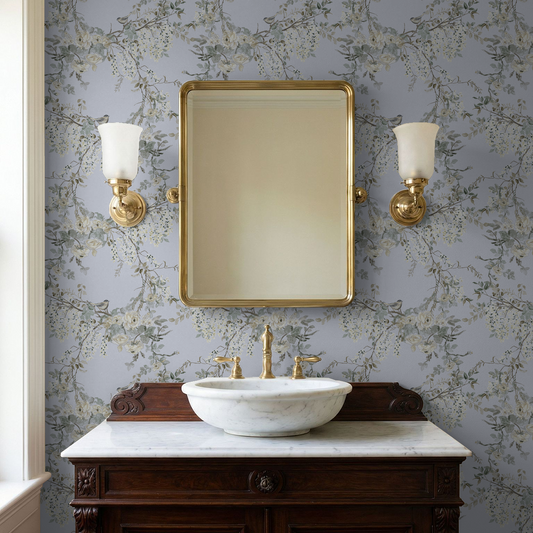 Bathroom vanity with marble sink, gold fixtures, and wall-mounted mirror against floral wallpaper.