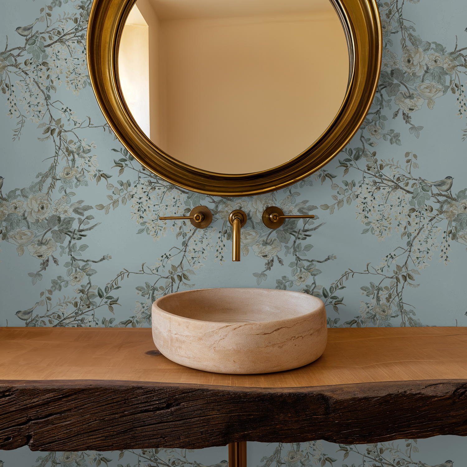 Bathroom vanity with a round beige sink, gold faucet, and mirror against floral wallpaper.