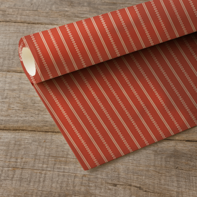 Roll of red striped wrapping paper on a wooden surface
