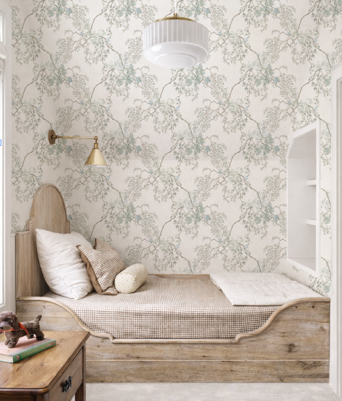 Nook with wooden bench, pillows, and a small table against floral wallpaper.