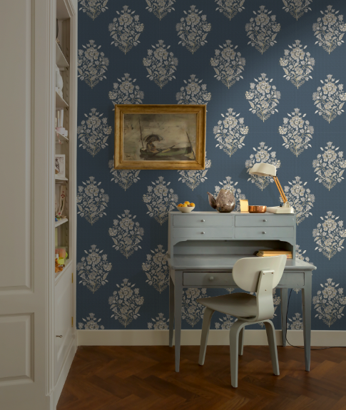 Room interior with blue floral wallpaper, desk, and chair.