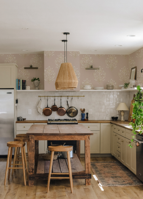Kitchen with wooden island, stools, and various kitchen items.