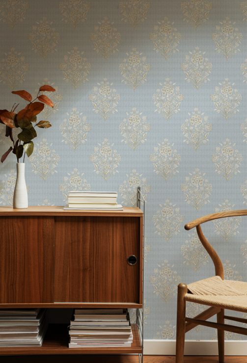 Wooden sideboard with books and a vase against a patterned wallpaper wall.