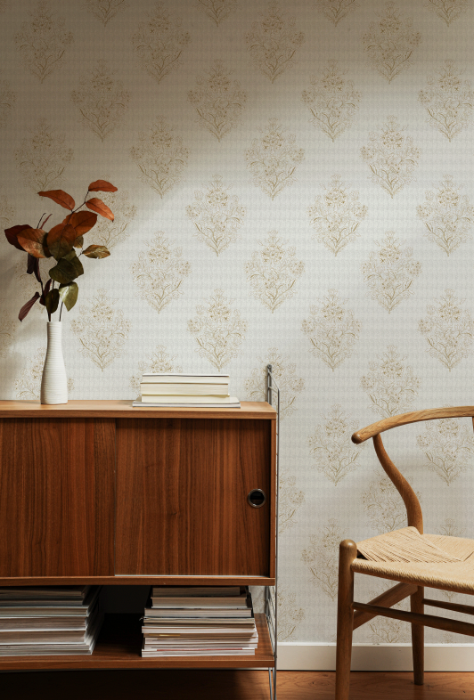 Wooden sideboard with books and a vase against a patterned wall.
