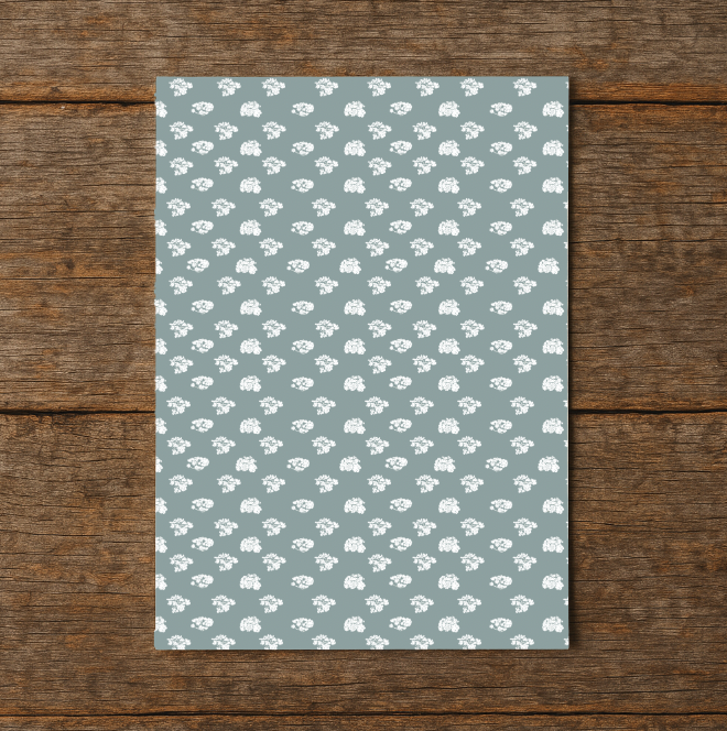 Notebook with a white floral pattern on a blue background, placed on a wooden surface.