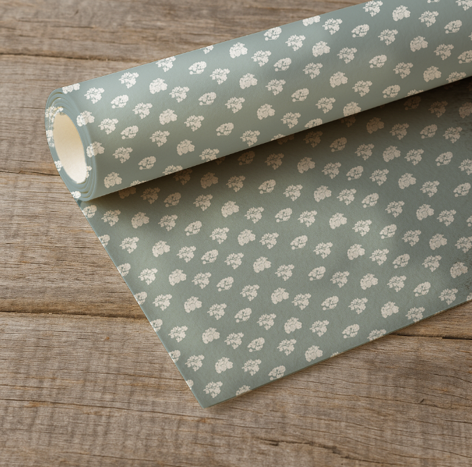 Roll of green floral patterned paper on a wooden surface