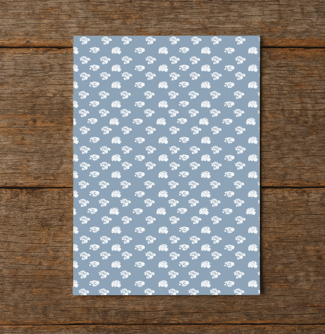 Notebook with white floral pattern on blue cover, placed on a wooden surface
