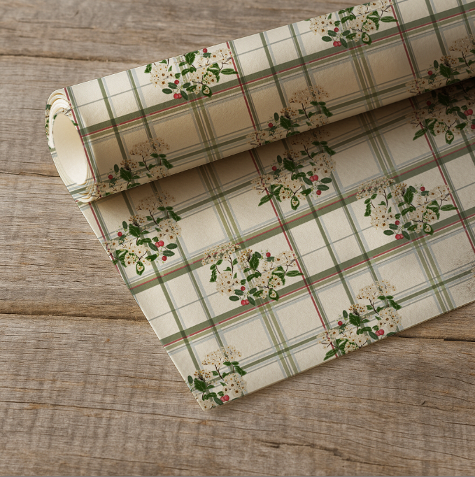 Roll of plaid wrapping with floral patterns on a wooden surface