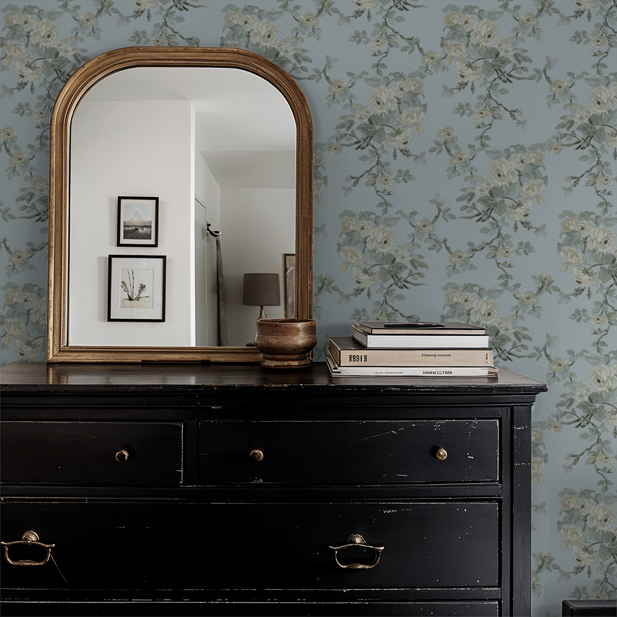Blue floral wallpaper with mirror and black dresser in vintage room.