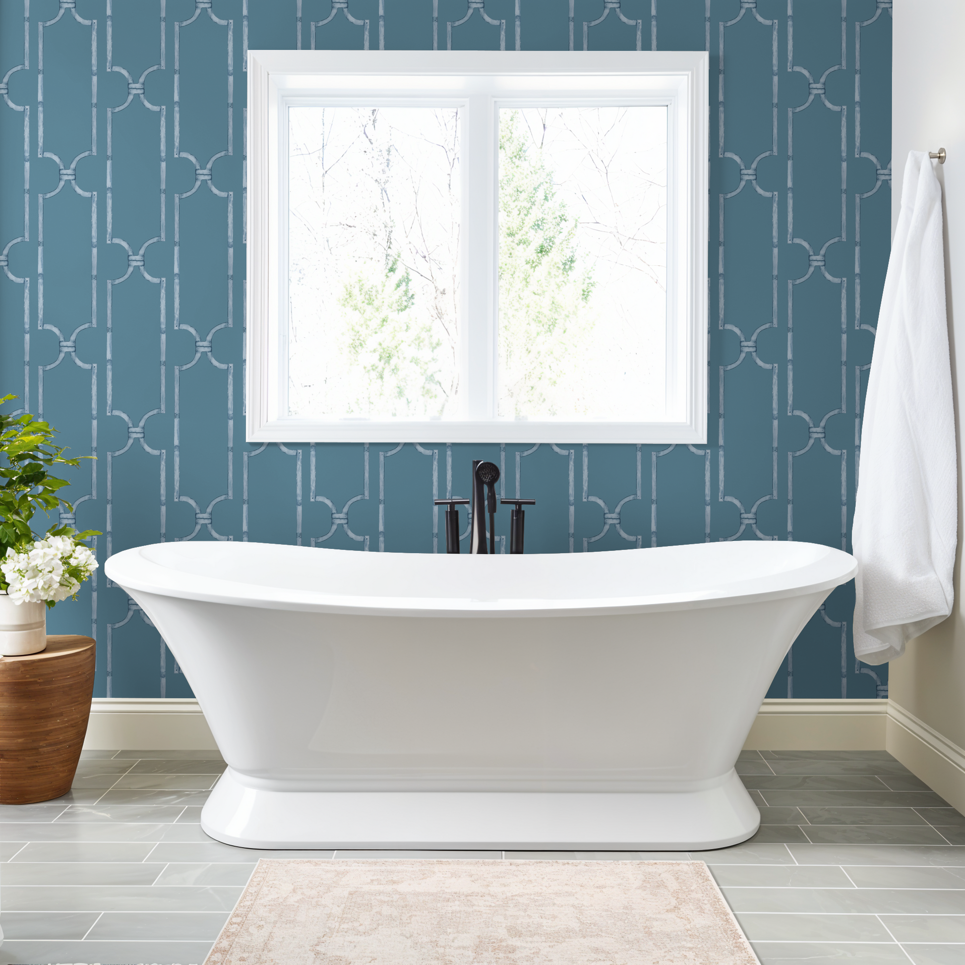 Blue trellis wallpaper in modern bathroom with white tub and window.