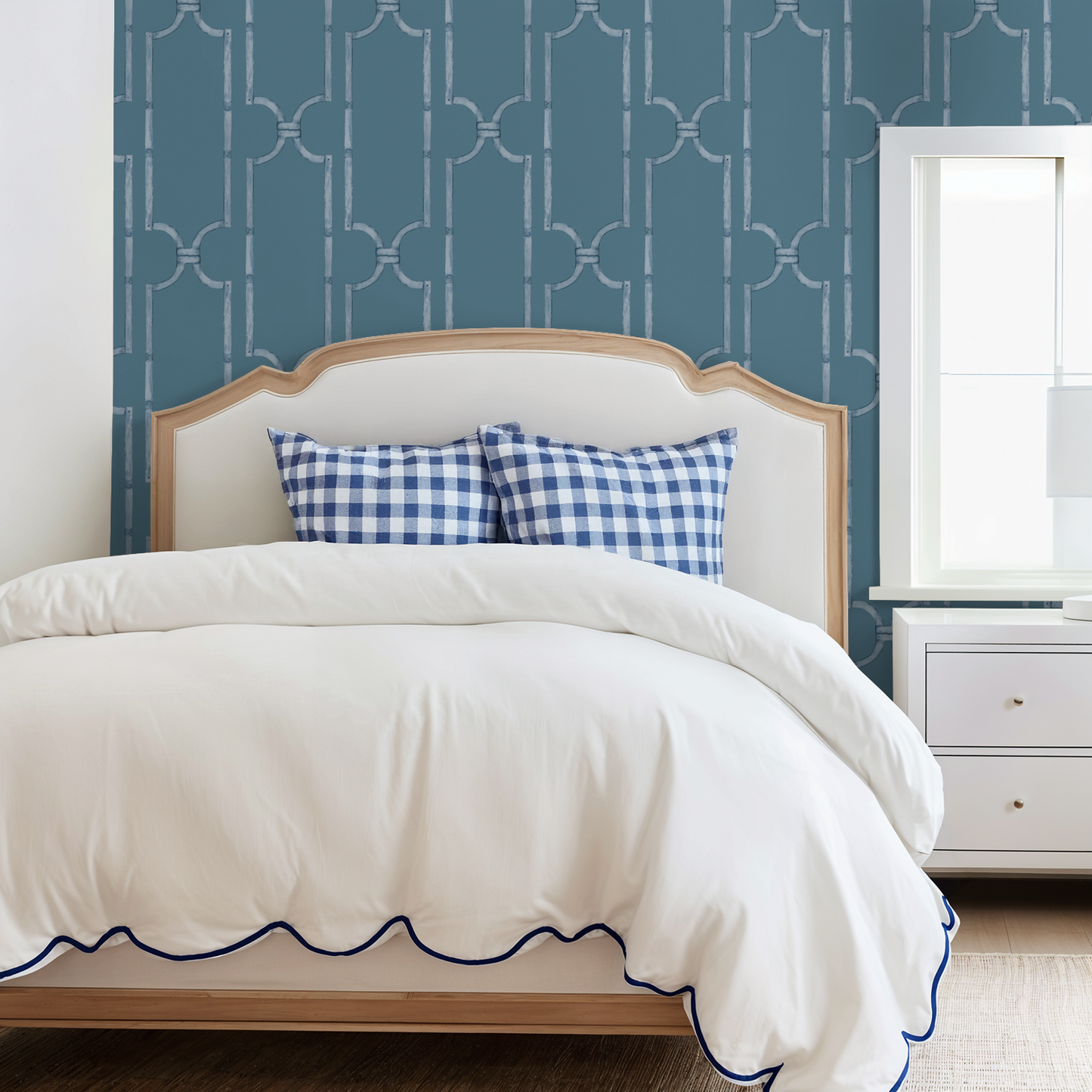 Blue wood trellis wallpaper in bedroom with white bed and checkered pillows.