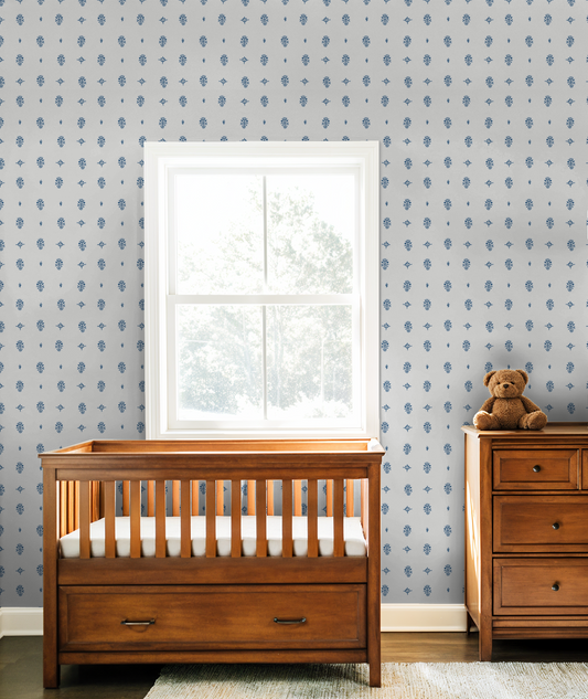 Cream and blue botanical wallpaper in a nursery with wooden crib and dresser.
