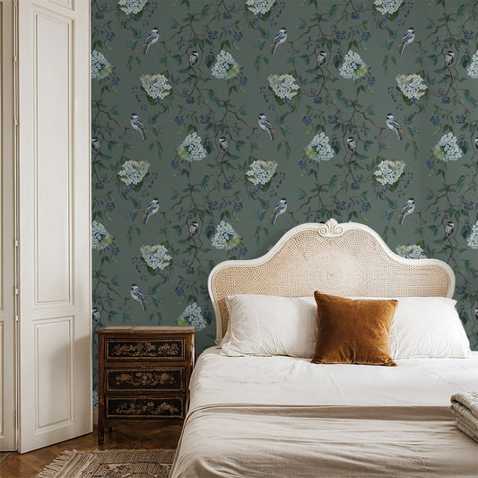 Floral and bird motif wallpaper in a cozy bedroom setting with a vintage headboard.