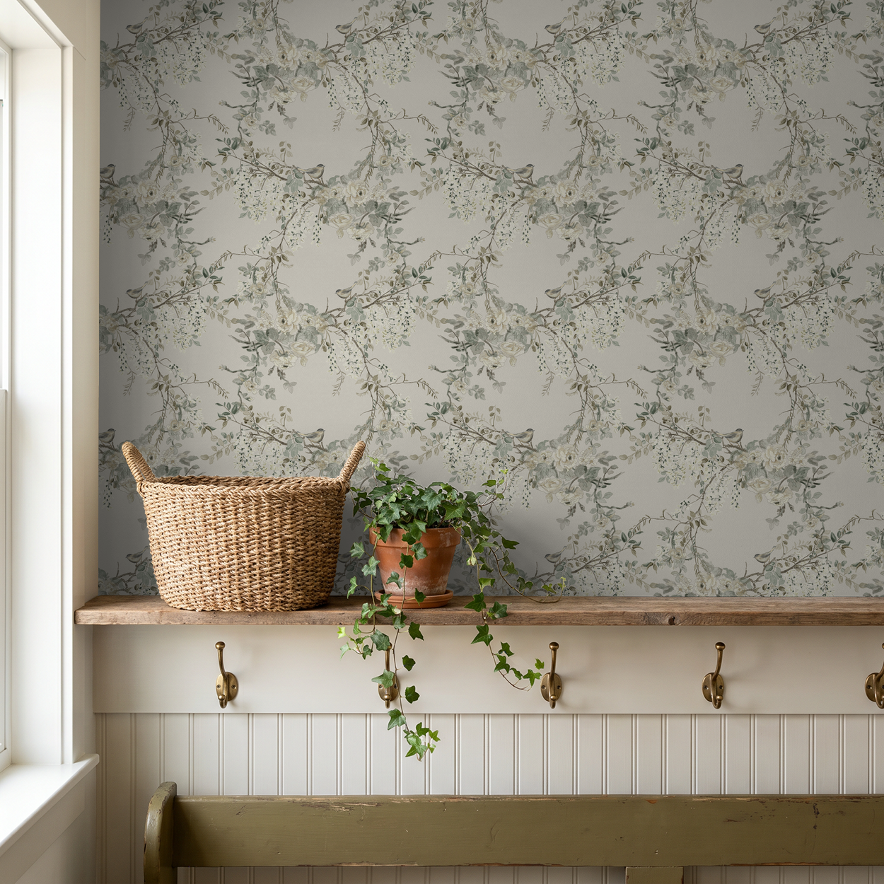 Floral wallpaper with delicate branches and blossoms in soft greens and creams in a cozy room setting.