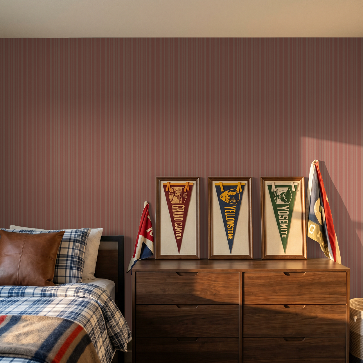 Warm coral and peach striped wallpaper in cozy bedroom with wooden dresser and flags.