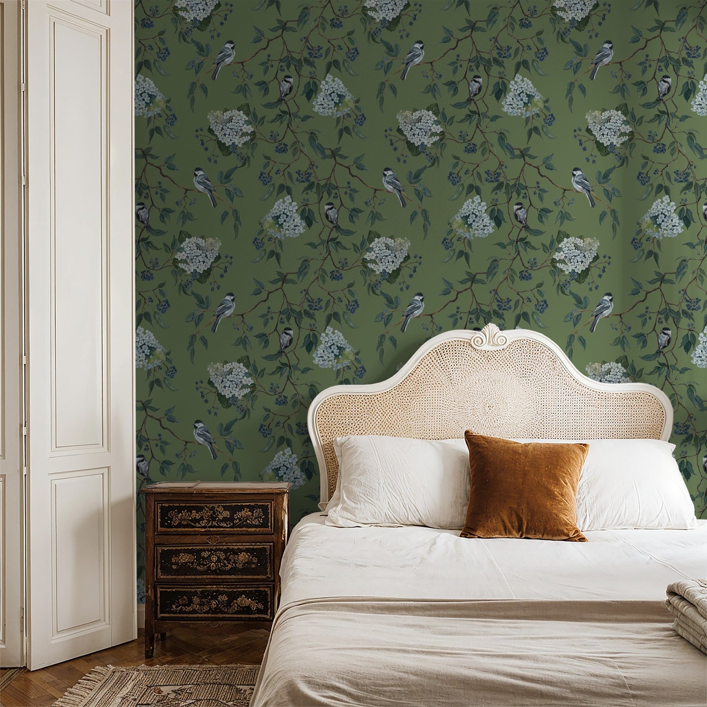 Green floral and bird wallpaper in elegant bedroom with wicker headboard.