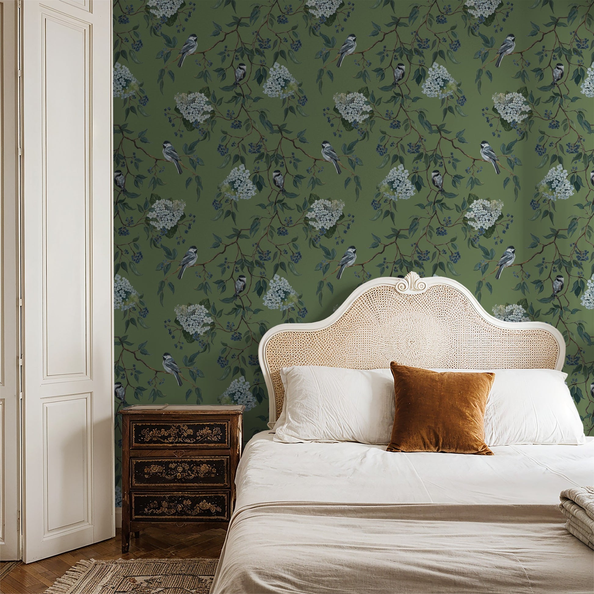 Green floral and bird wallpaper in elegant bedroom with wicker headboard.