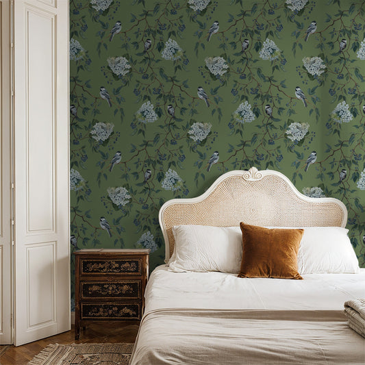 Green floral and bird wallpaper in elegant bedroom with wicker headboard.