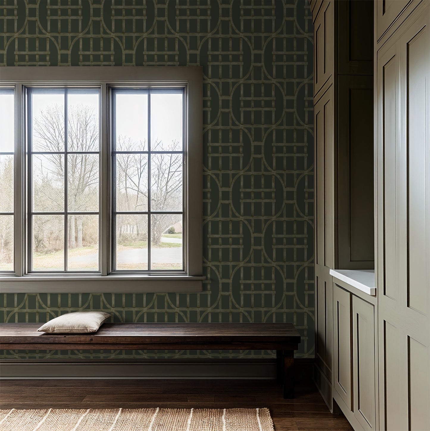 Trellis patterned wallpaper in green and brown in a rustic entryway with bench and window.
