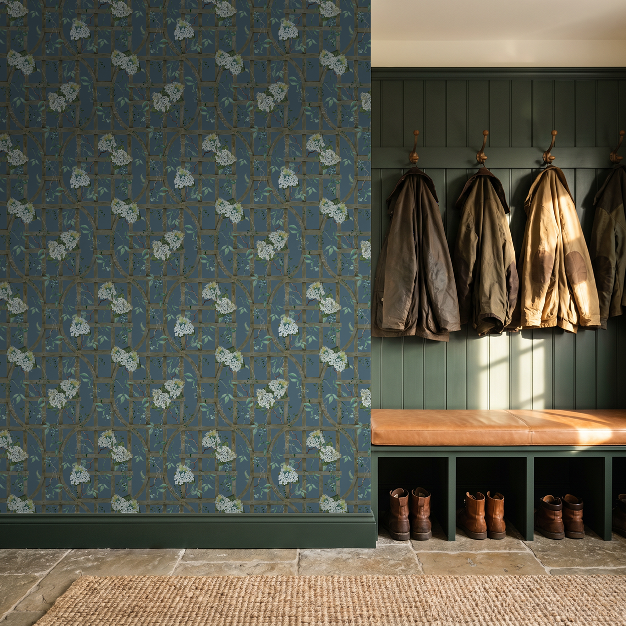 Hydrangea trellis wallpaper on deep blue in rustic entryway with coats and boots.