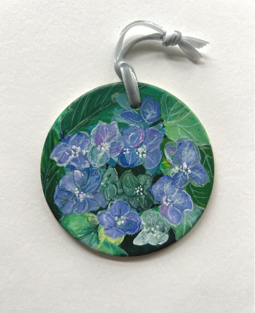 Round pendant with blue floral design on a white background