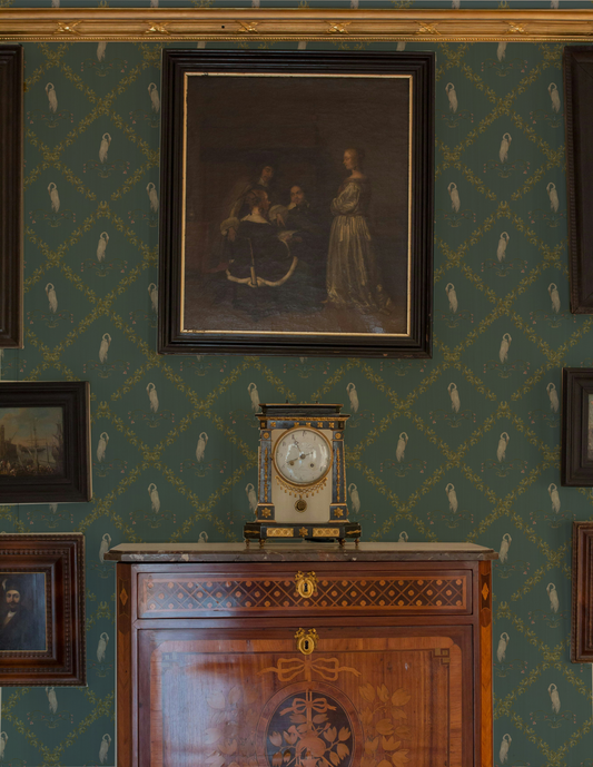 Decorative wall with framed artwork and a clock on a wooden cabinet.