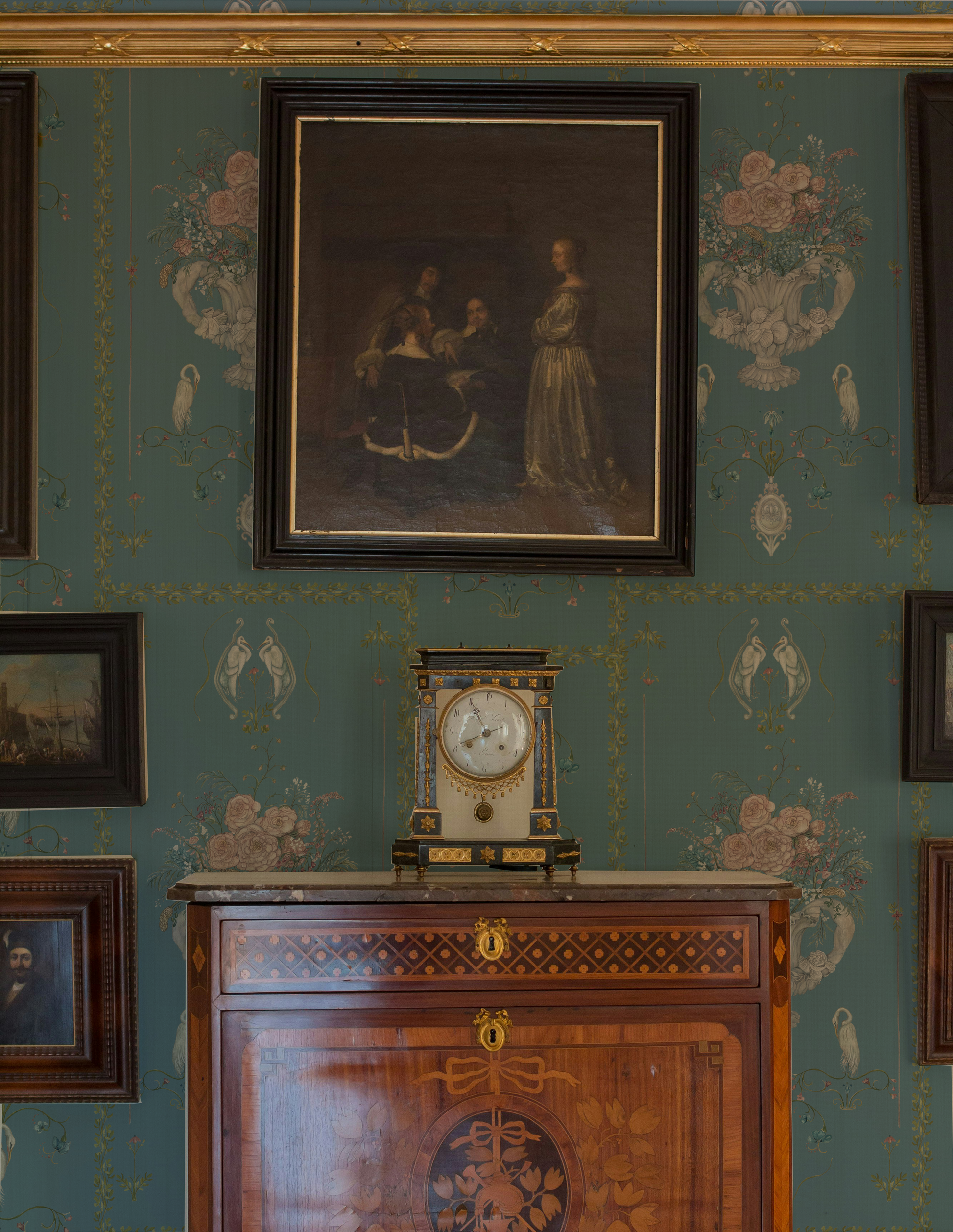 Decorative interior with a clock on a wooden cabinet against a patterned wall.