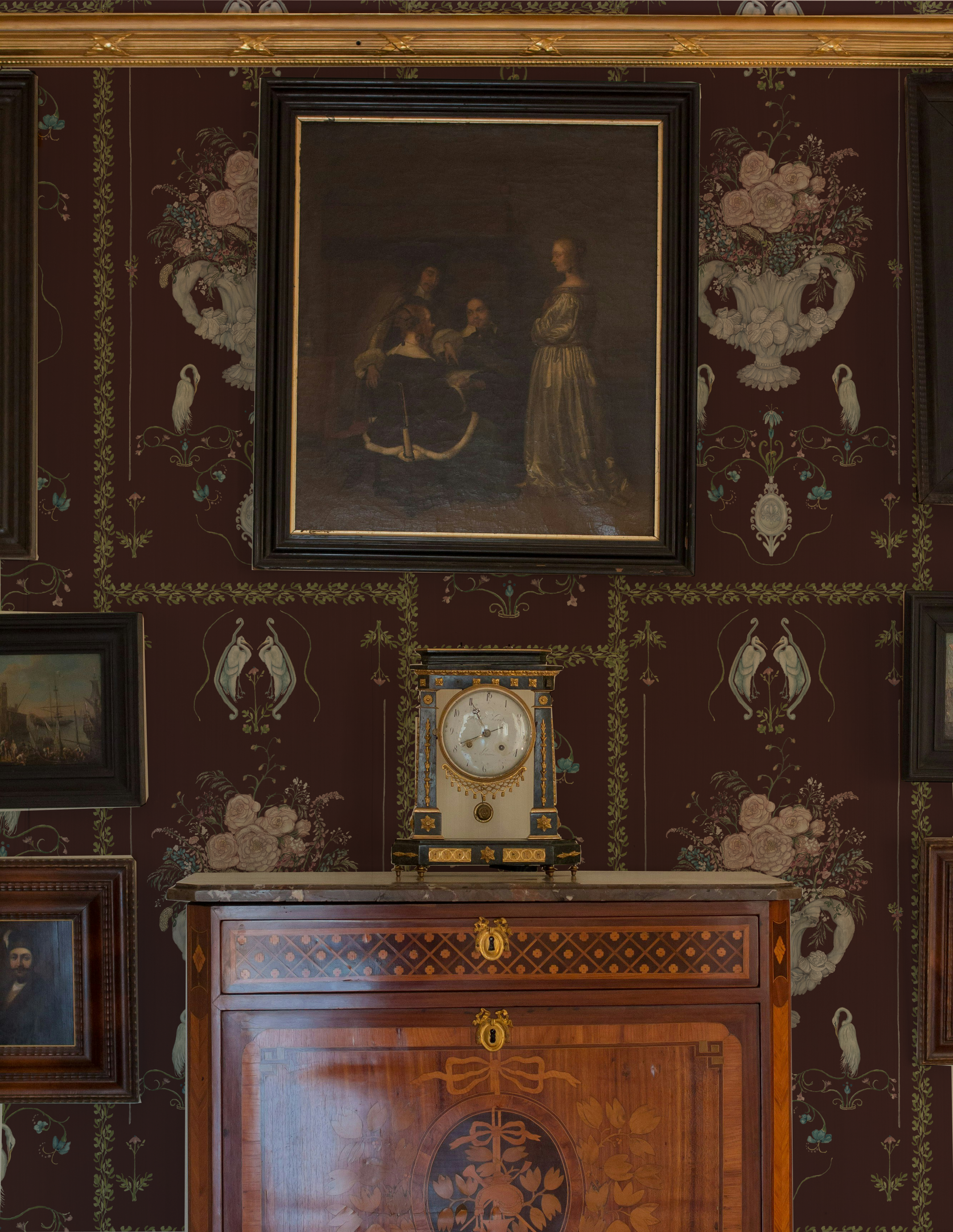 Decorative interior with a portrait, clock, and wooden cabinet against a patterned wall.