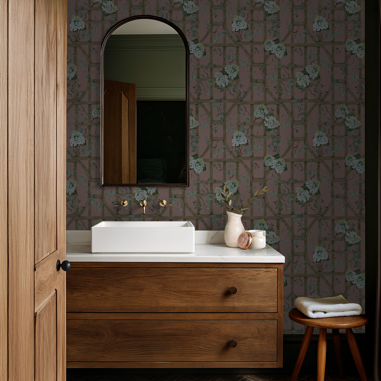 Bathroom with mauve hydrangea trellis wallpaper, wooden vanity, and mirror.