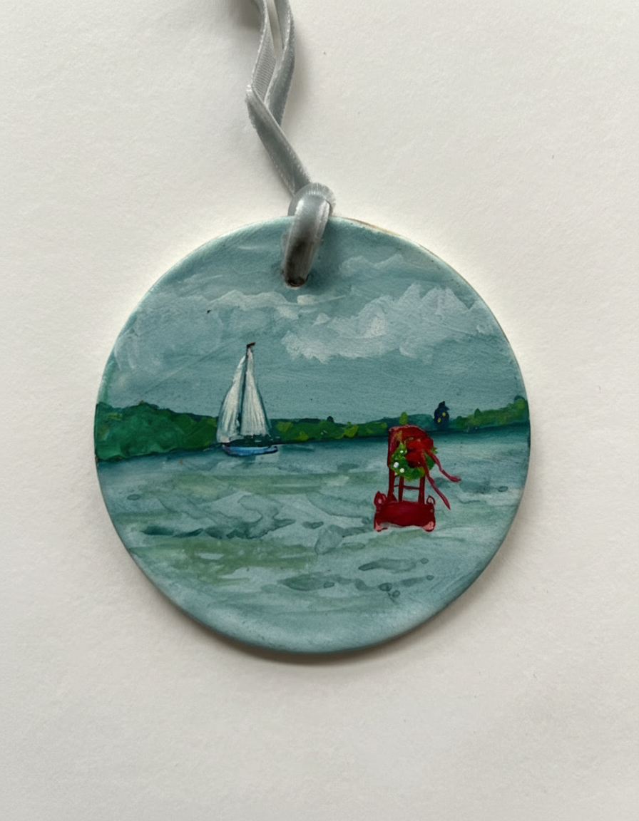 Round painted pendant with a sailboat and lifeguard chair on water, on a white background