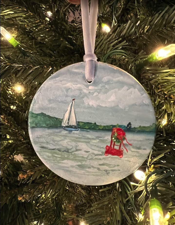 Decorative Christmas ornament with a sailboat and red chair on a tree.