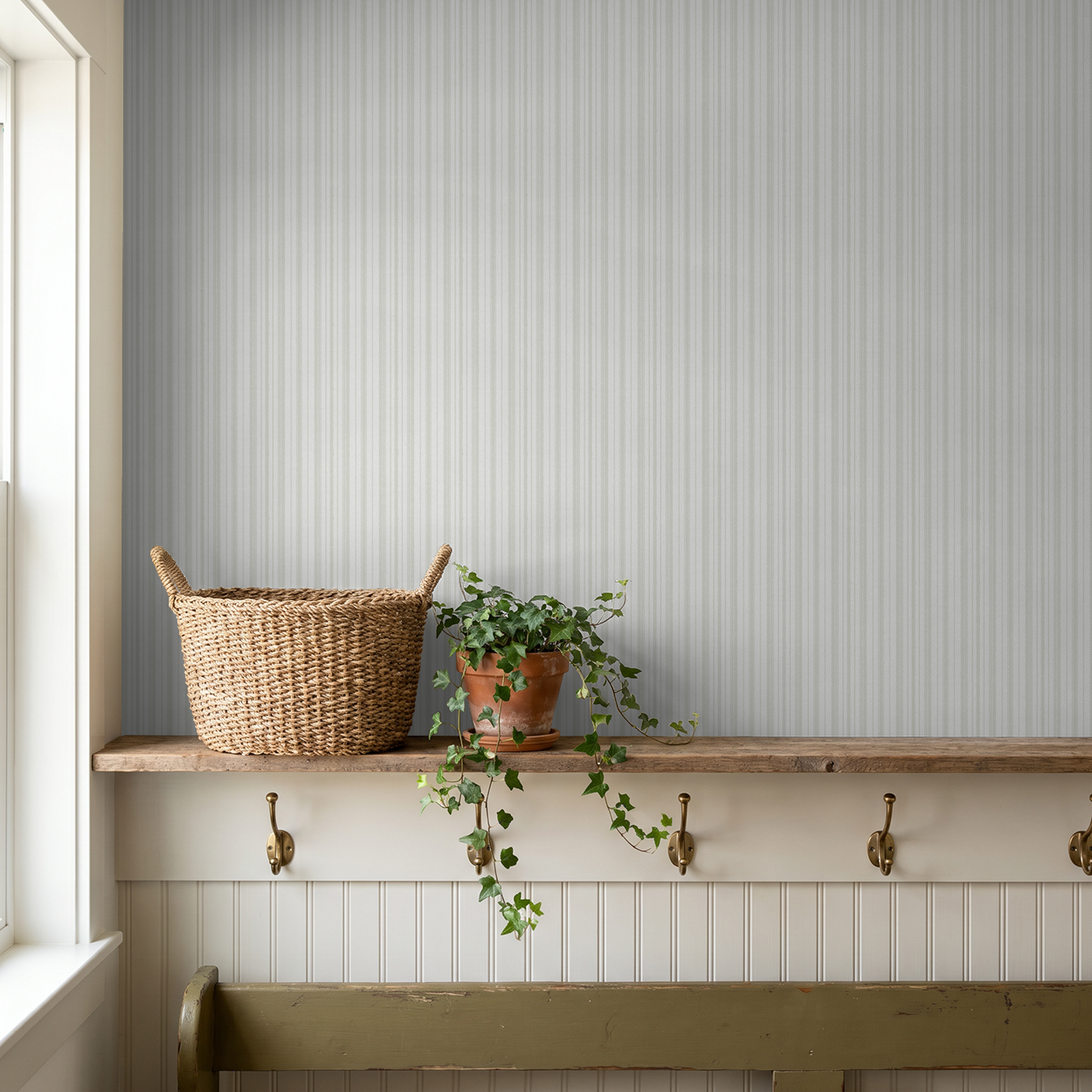 Soft green striped wallpaper in rustic room with wicker basket and plant.