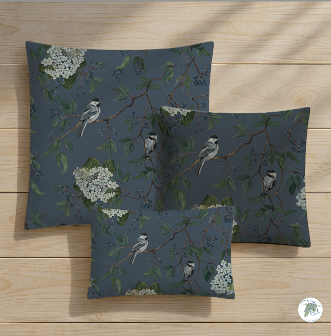 Set of three decorative pillows with bird and branch pattern on a wooden surface