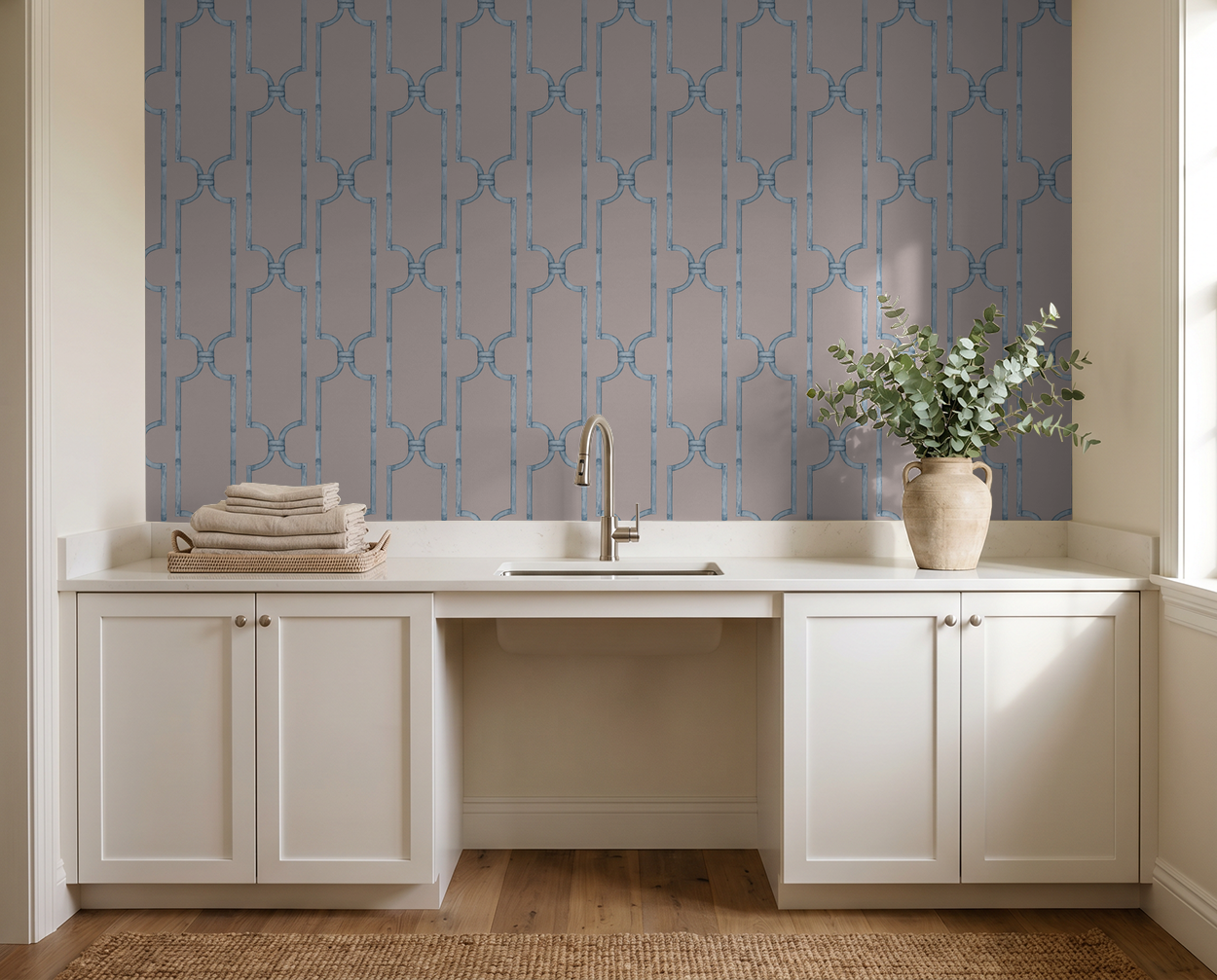 Trellis blue geometric wallpaper in modern laundry room with white cabinets and vase.
