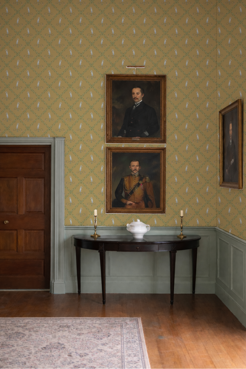 Room with portraits on the wall and a table with a vase and candles.