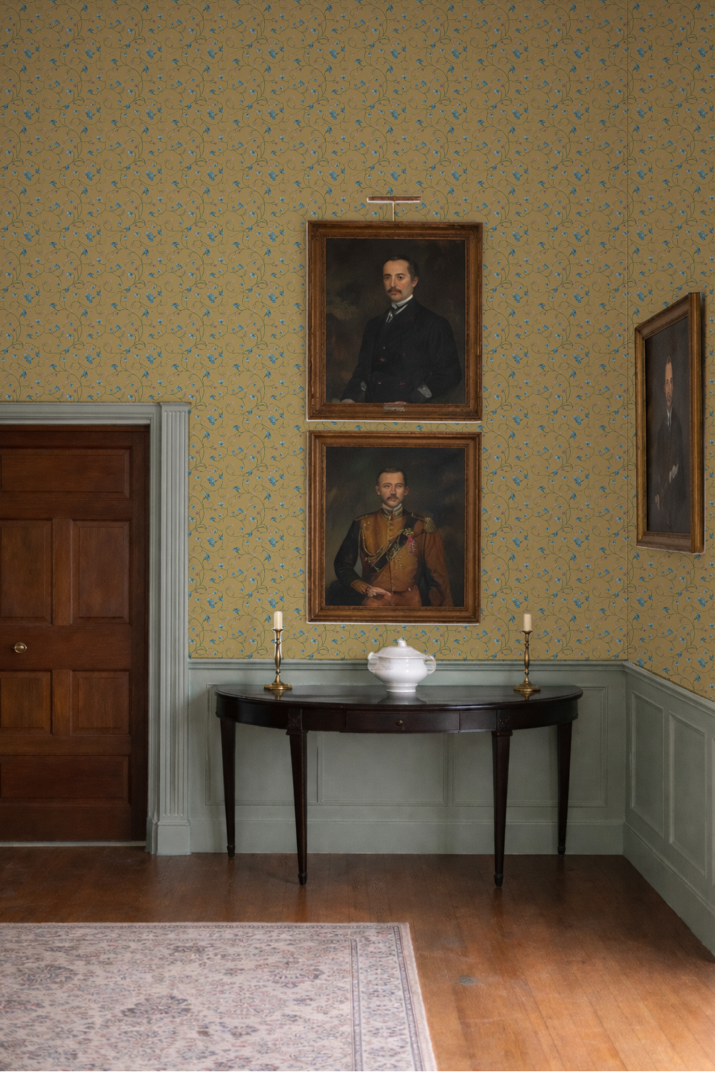 Room with portraits on the wall and a table with decorative items.