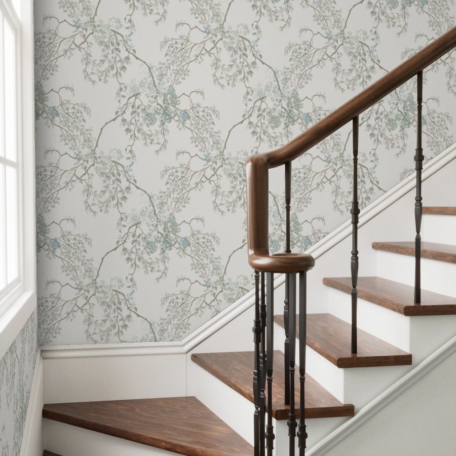 Staircase with wooden steps and handrail against a floral wallpapered wall.