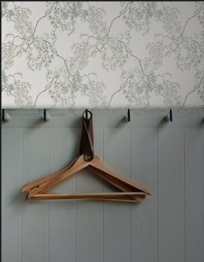 Wooden hanger on a hook against a floral wallpapered wall.